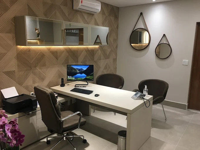 Sala de atendimento ampla e iluminada, com mesa, computador e poltronas